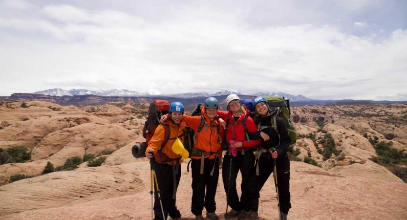 A group of people wearing safety gear smile for a photo in a high desert landscape